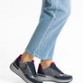 Pair of gray sneaker with red and gold highlights worn by someone with blue jeans