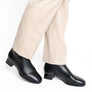 Black leather shoes worn by someone with beige pants