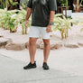 Man wearing gray t-shirt and white pants wearing black slip-on sneakers