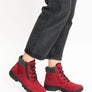 Red winter boots with zippers worn by someone in gray jeans