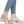 Metallic beige sandals worn by someone in blue jeans